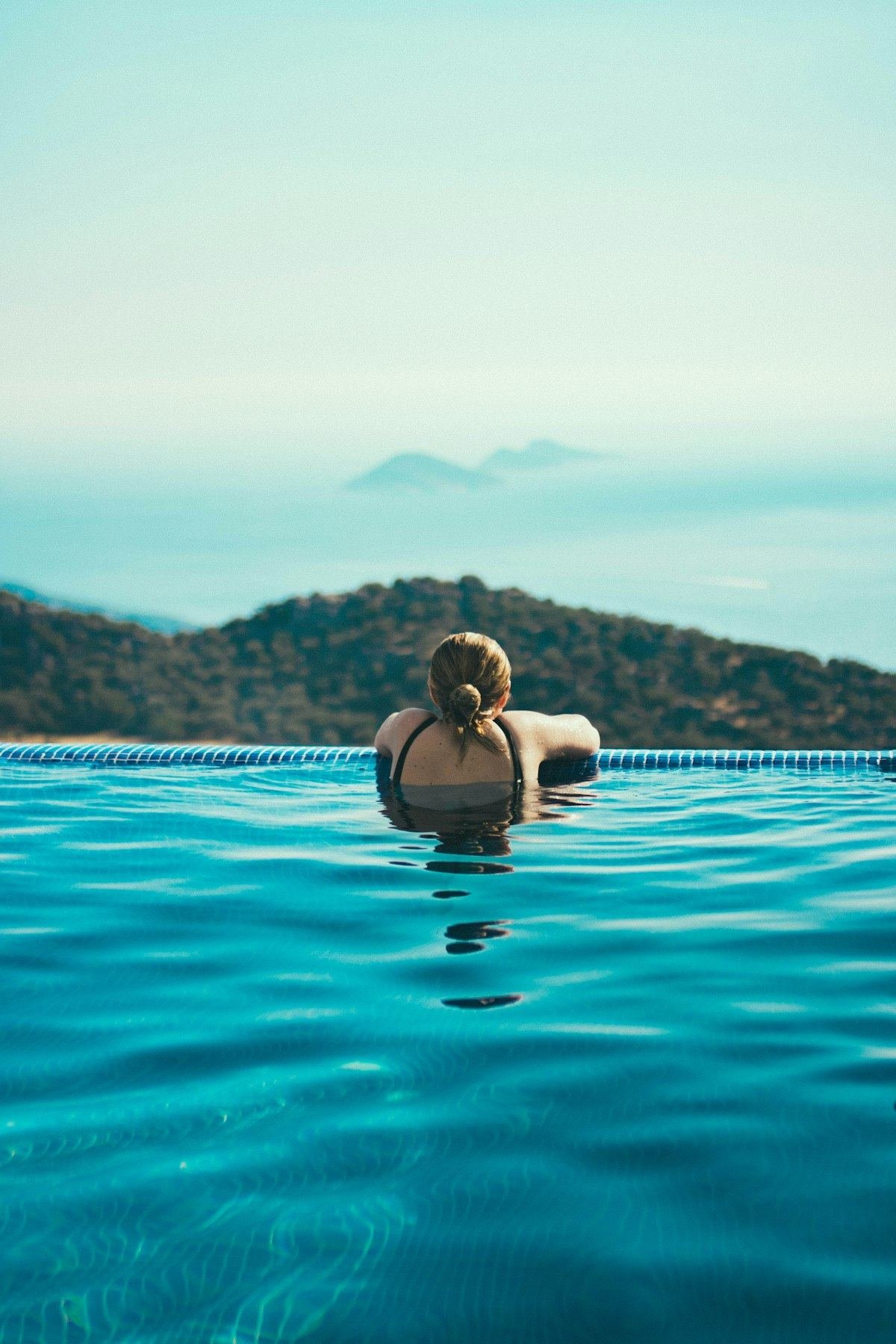 Woman relaxing in an infinity pool overlooking the sea